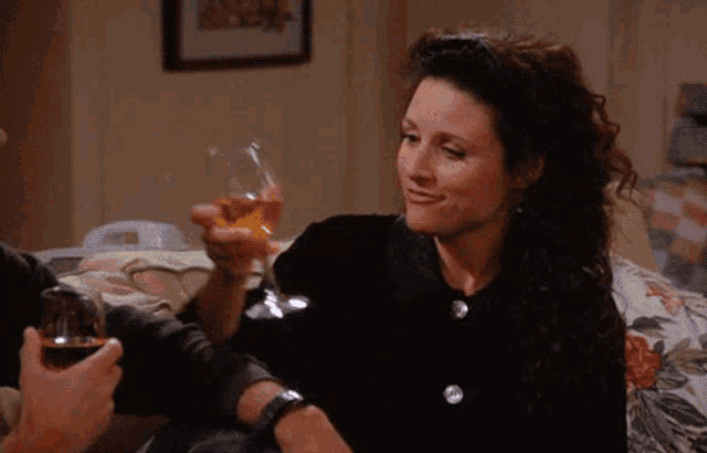 a woman is smiling while holding a glass of wine