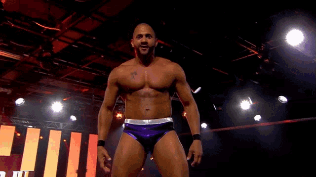 a wrestler with a tattoo on his chest is standing in front of a sign that says ' ii '