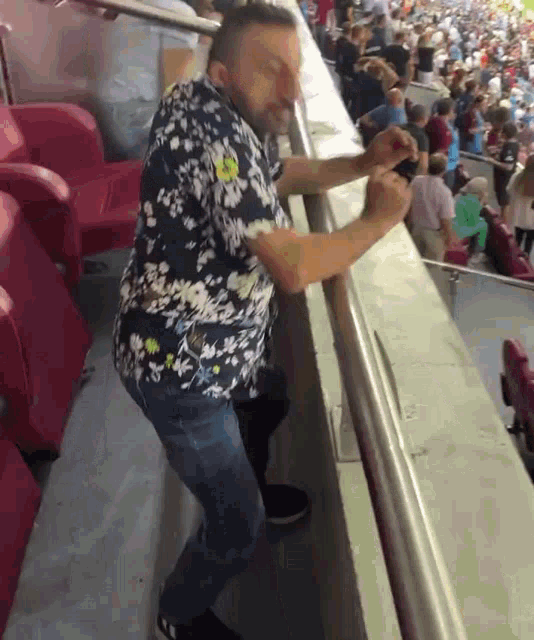 a man in a floral shirt is standing on a balcony