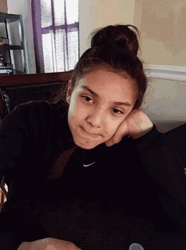 a young girl wearing a black nike sweatshirt looks tired