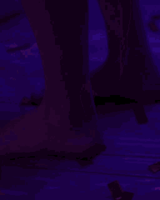 a person 's feet are visible in a dark room with purple lights .
