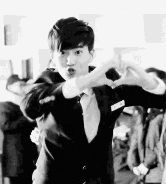 a man in a suit making a heart with his hands