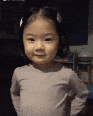 a little girl wearing a purple shirt and a white hair clip is smiling