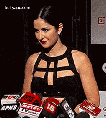 a woman is standing in front of a bunch of microphones and talking to them .