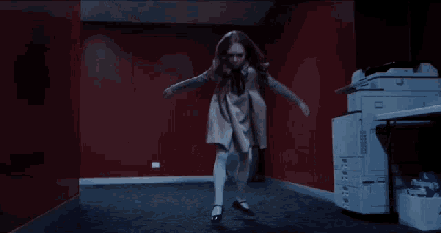 a little girl in a white dress dancing in a hallway