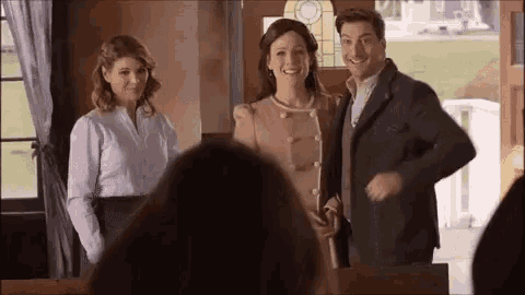 a group of people are standing next to each other in a room and smiling .