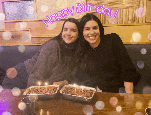 two women sitting at a table with candles and the words happy birthday