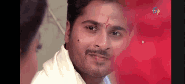 a man with a red circle on his forehead looks at a woman .