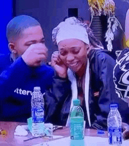 a man and a woman are sitting at a table with bottles of water on it .