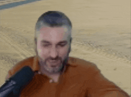 a man with a beard is sitting in front of a microphone on a beach .