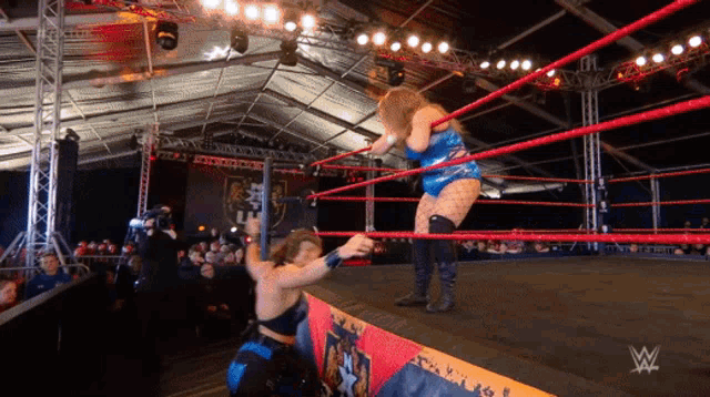 two women are wrestling in a ring with a w logo on the corner