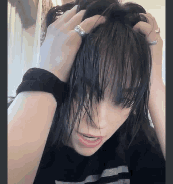 a woman with a ring on her finger holds her hair