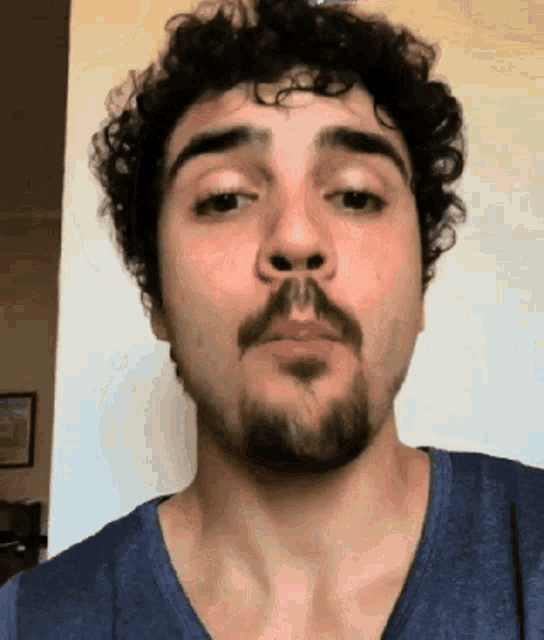 a man with curly hair and a beard is making a face