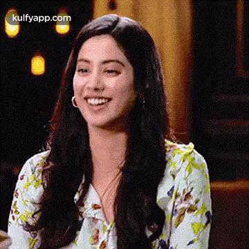 a woman with long hair is smiling for the camera while wearing a floral shirt .