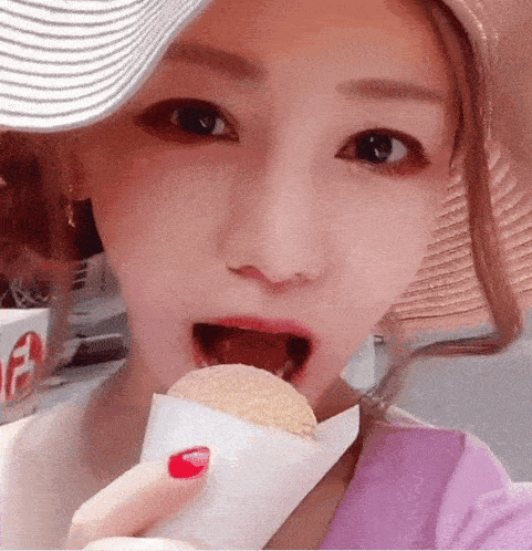 a woman wearing a hat is eating an ice cream cone with the letter e on it