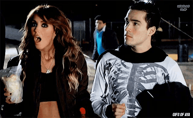 a man in a skeleton shirt is standing next to a woman