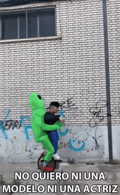 a man in a green alien costume is riding a unicycle