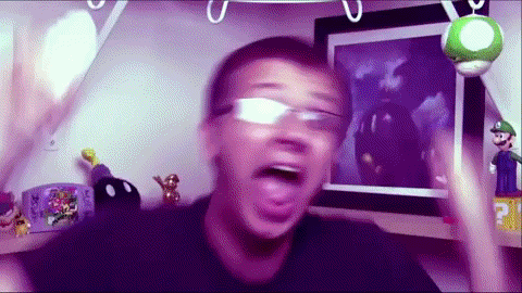 a man wearing glasses is making a funny face in front of a picture of luigi
