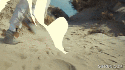 a gif from gifrun.com shows a person riding a skateboard in the sand