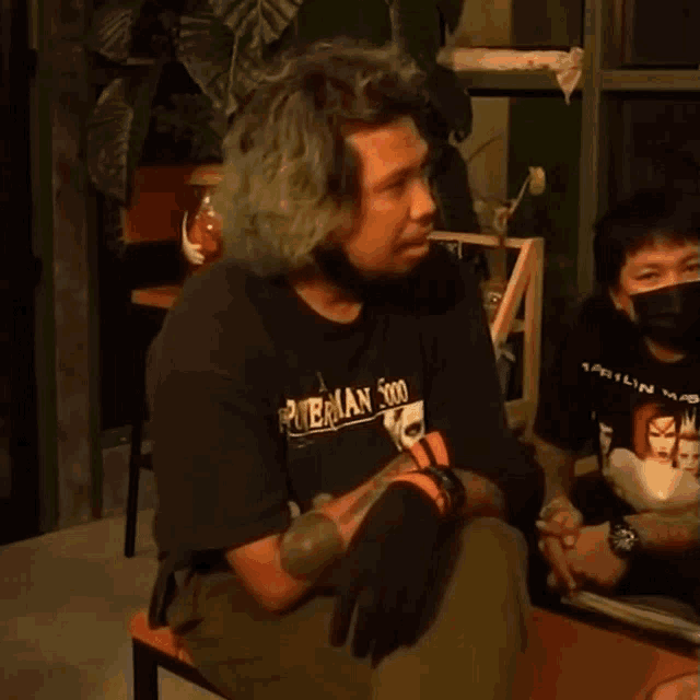 a man wearing a black shirt that says powerman 500 laughs