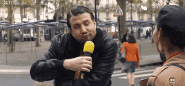 a man is holding a yellow microphone while talking to a woman on the street