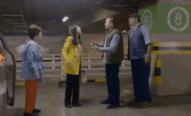 a group of people are standing in a parking garage fighting .