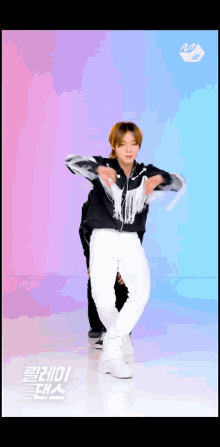 a man in a black jacket and white pants is dancing in front of a colorful background
