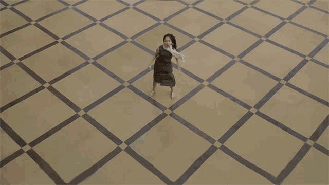a woman in a black dress is running on a checkered tile floor