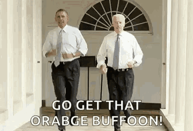 two men in suits and ties are walking down a hallway and dancing .