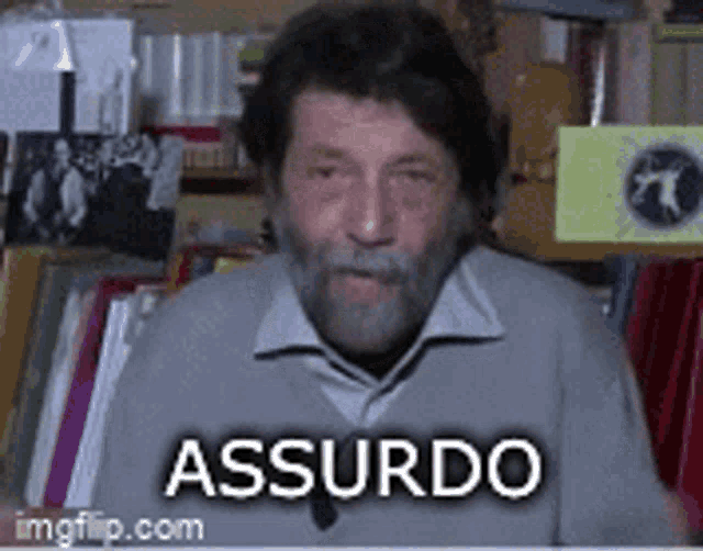 a man with a beard is sitting in front of a bookshelf and has the word assurdo on the bottom