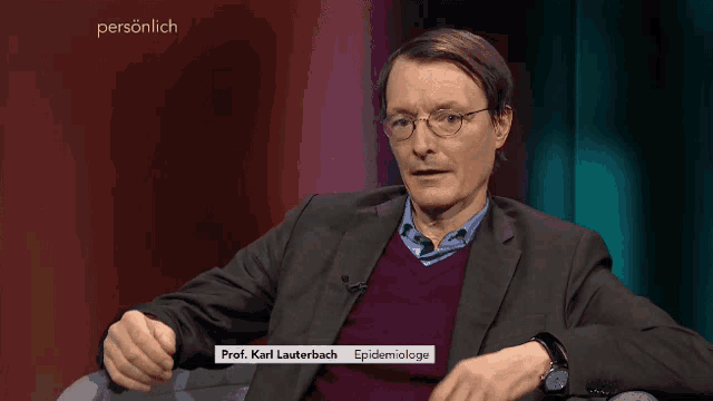 a man in a suit and glasses is sitting in front of a red curtain and says prof. karl lauterbach epidemiologe