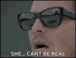 a man wearing sunglasses is holding a pair of sunglasses in his hand .