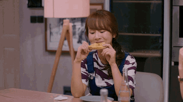 a woman sitting at a table eating a slice of pizza