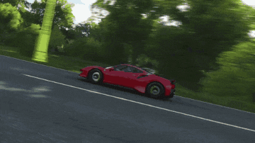 a red sports car driving down a road with trees in the background