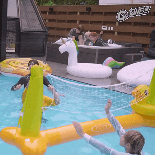 people playing volleyball in a pool with a sign that says go one on it