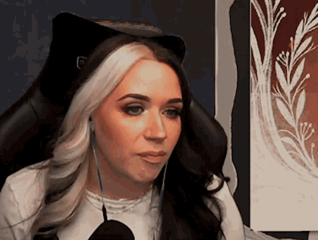 a woman wearing headphones and a cat ear headband looks at the camera .