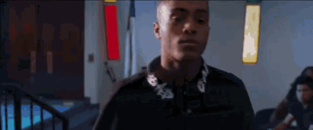 a man in a black shirt is standing in a dark room in front of a window .