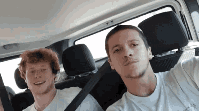 two men are sitting in the back seat of a car and one is wearing a t-shirt that says abercrombie