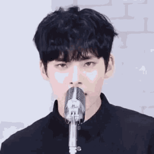 a young man is singing into a microphone and making a funny face .
