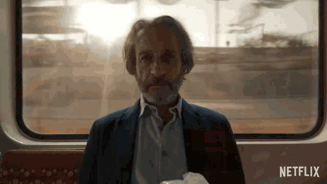 a man sitting on a train with a netflix logo on the bottom right