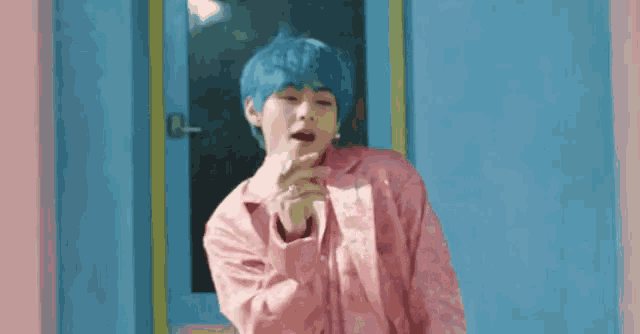 a young man with blue hair is wearing a pink jacket and a pink shirt .