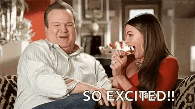 a man and a woman are sitting on a couch and the woman is eating a candy bar .