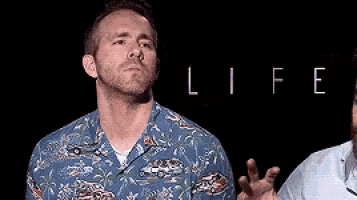 a man in a hawaiian shirt is making a funny face in front of the word life .