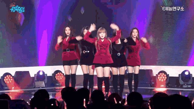 a group of girls are dancing on a stage with a blue sign that says ' love '