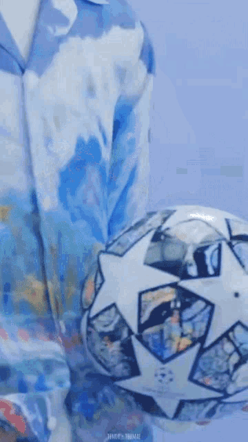 a person in a blue shirt is holding a soccer ball in their hand .