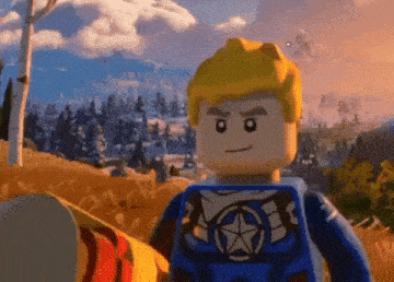 a lego captain america figure is standing in a field with a mountain in the background .