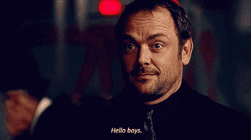 a man with a beard says hello boys in a dark room