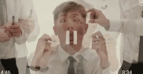 a man in a white shirt and tie is surrounded by people holding objects in their hands .