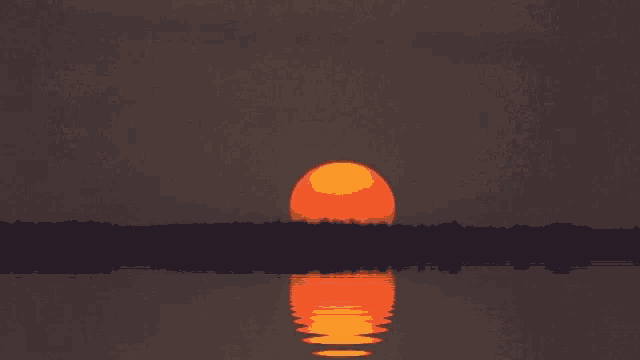 the sun is setting over a body of water with trees in the background
