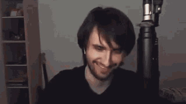 a man with a beard is making a funny face in front of a microphone in a room .